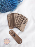 Set of brown faux leather tags with 'Stitches by Desire' branding on a white background.
