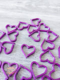 Purple heart 3D printed stitch markers on a wooden surface