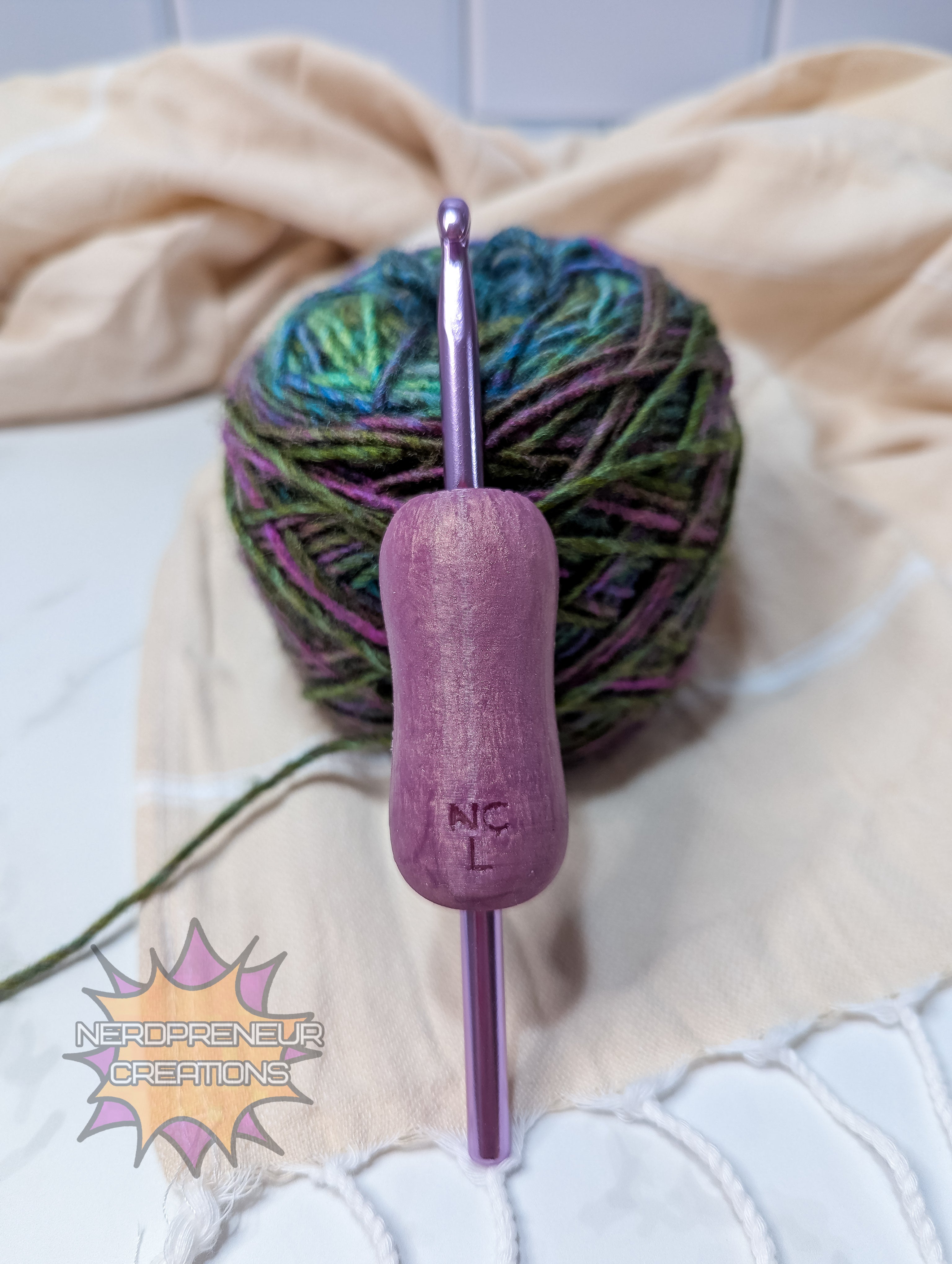 Pink silicone crochet grip with a ball of yarn on a beige blanket
