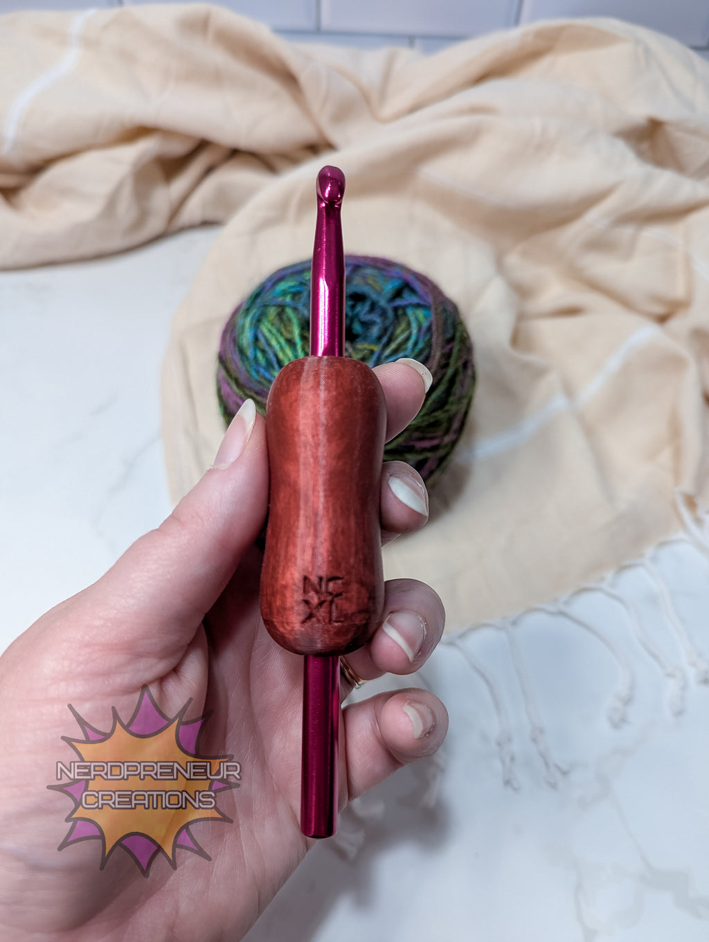 Hand holding a silicone crochet grip with a colorful yarn ball in the background