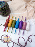 Set of colorful silicone crochet grip on a textured fabric background with yarn.