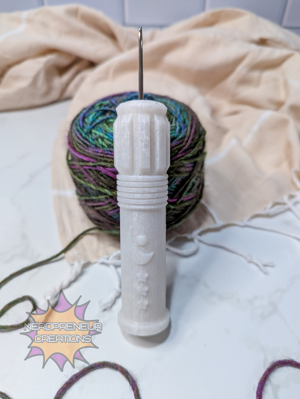 silicone crochet grip and ball of yarn on a white surface with a beige towel.