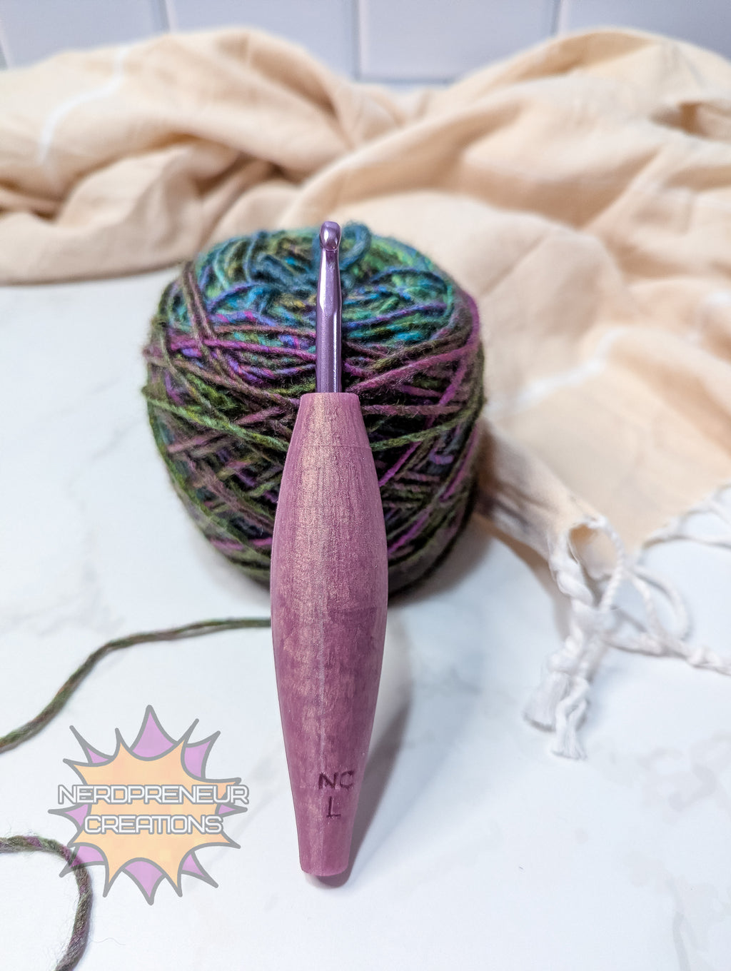 Pink silicone crochet grip with a ball of yarn on a white surface with a beige towel.