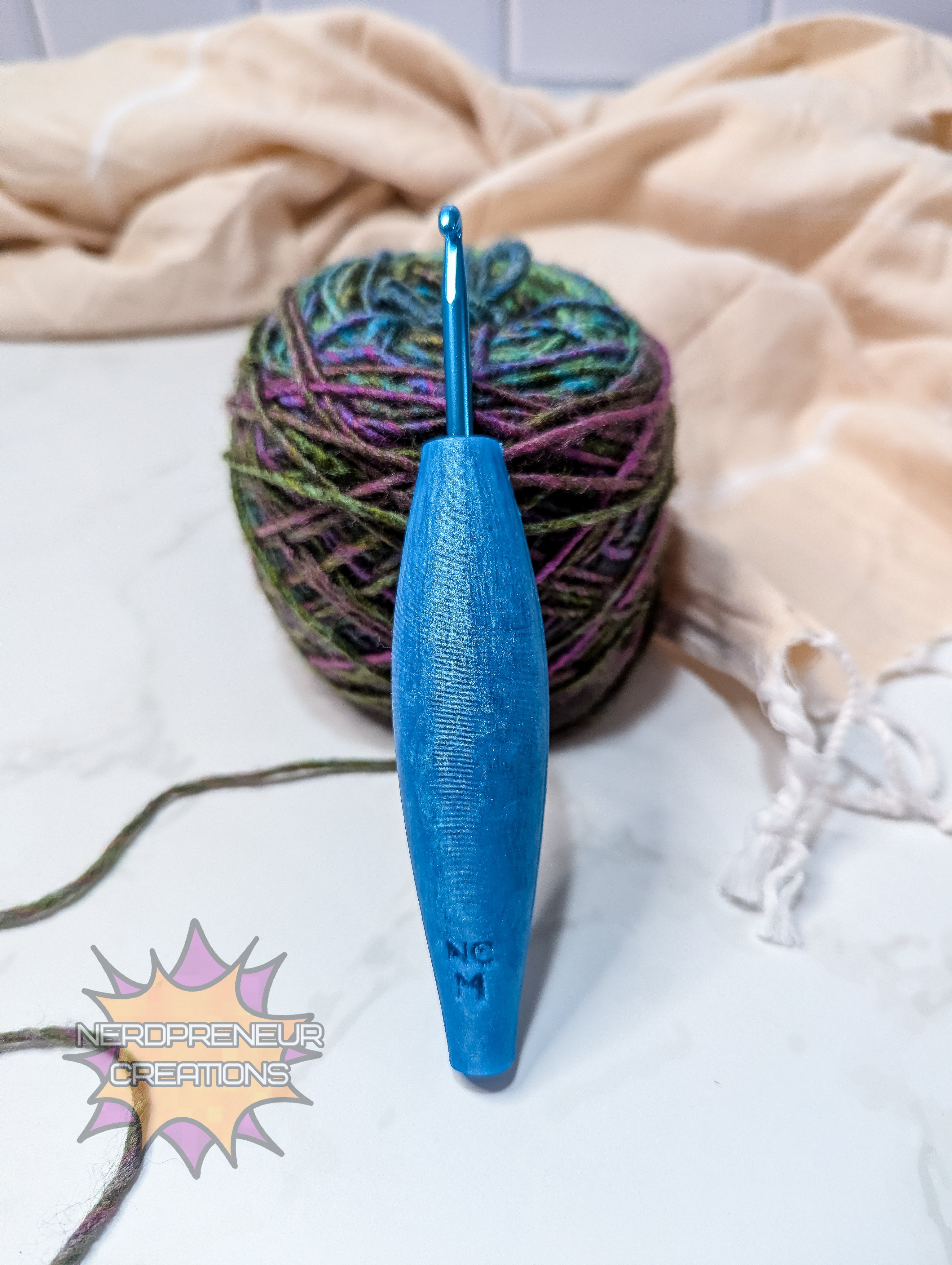 Blue silicone crochet grip next to a ball of multicolored yarn on a light background