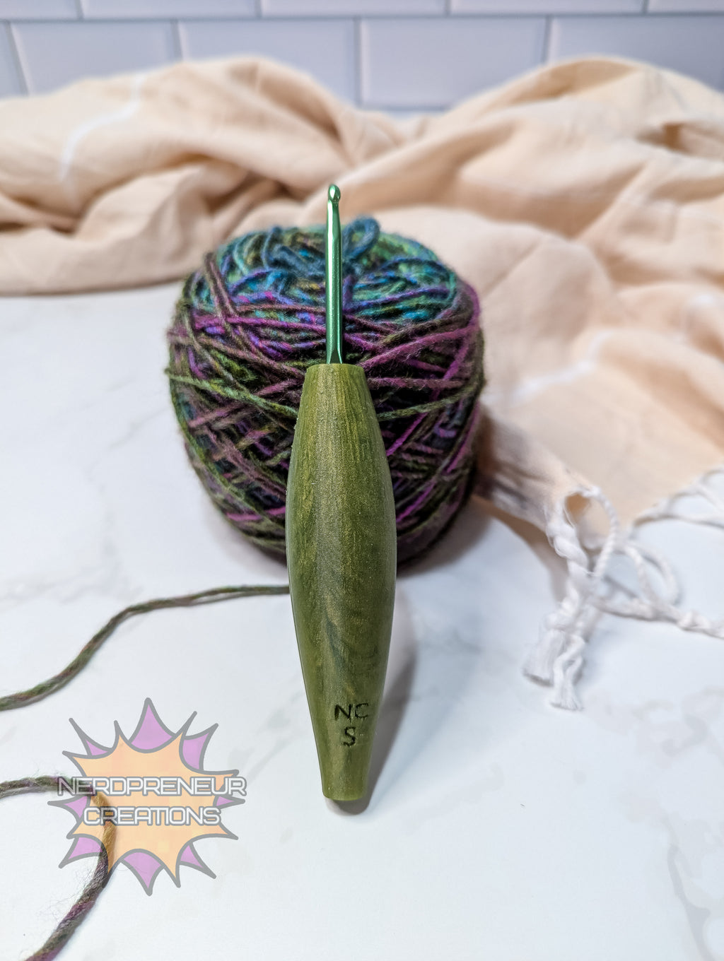 Green silicone crochet grip on a ball of multicolored yarn with a beige blanket in the background