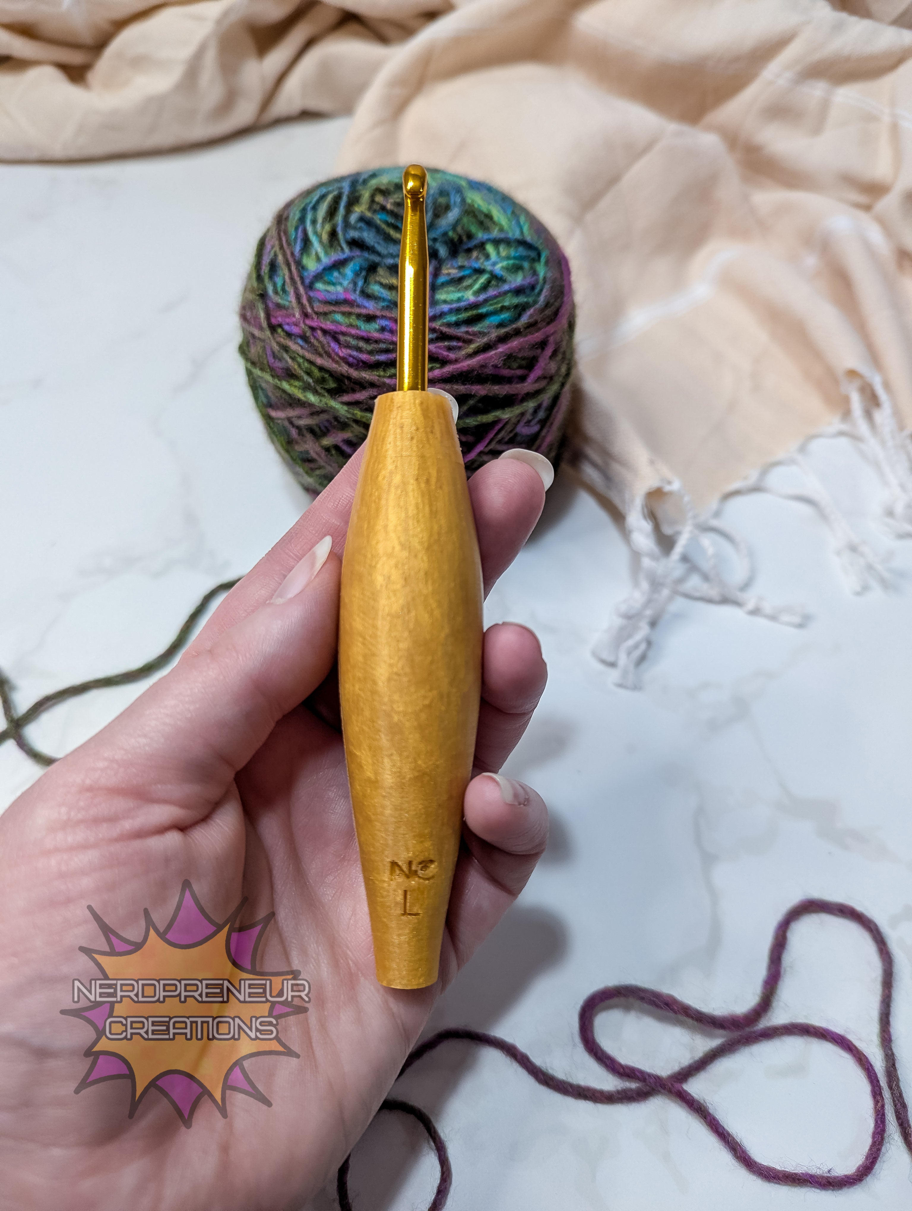 Hand holding a silicone crochet grip with colorful yarn on a textured fabric background