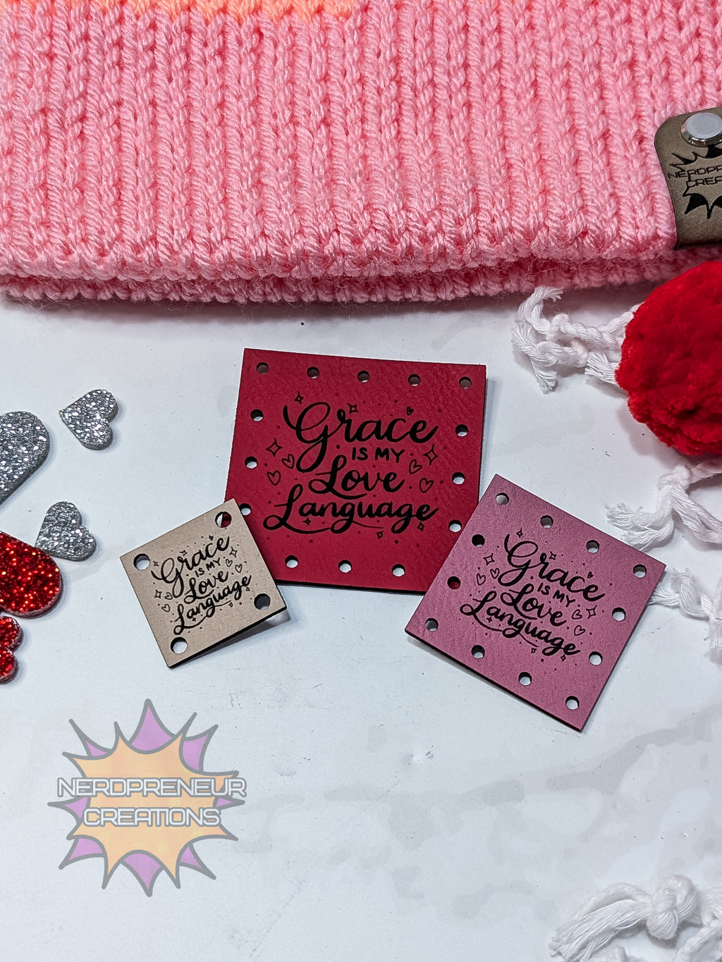 Decorative faux leather patches with 'Grace is my love language' text on a textured surface with pink fabric and decorative elements.