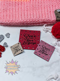 Decorative faux leather patches with 'Grace is my love language' text on a textured surface with pink fabric and decorative elements.