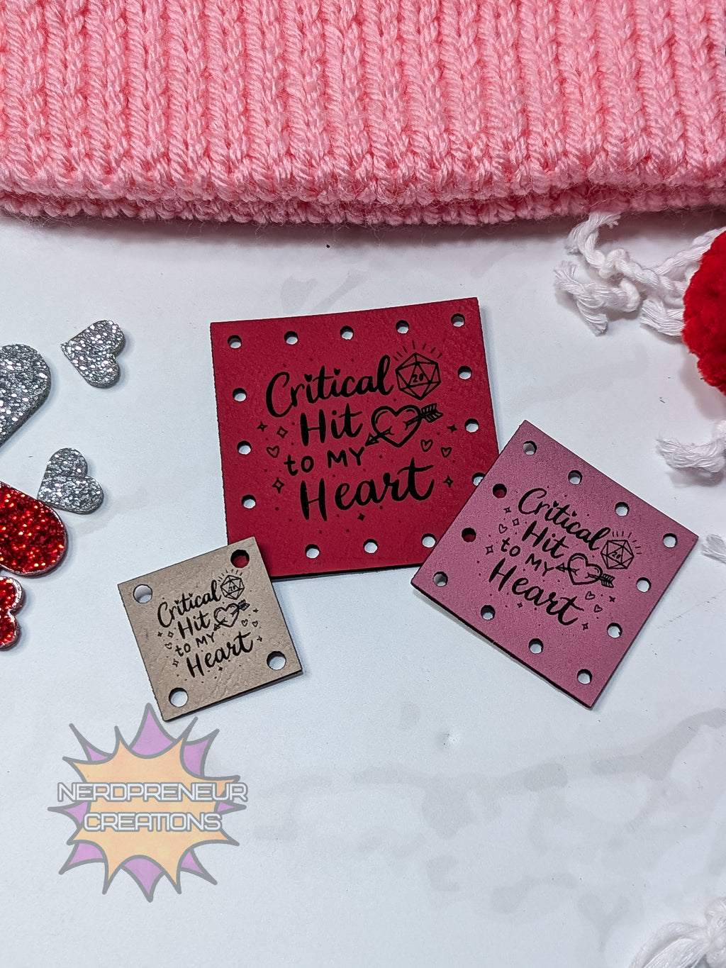 faux leather patches with 'Critical Hit to My Heart' text on a pink knitted fabric background.