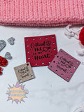 faux leather patches with 'Critical Hit to My Heart' text on a pink knitted fabric background.