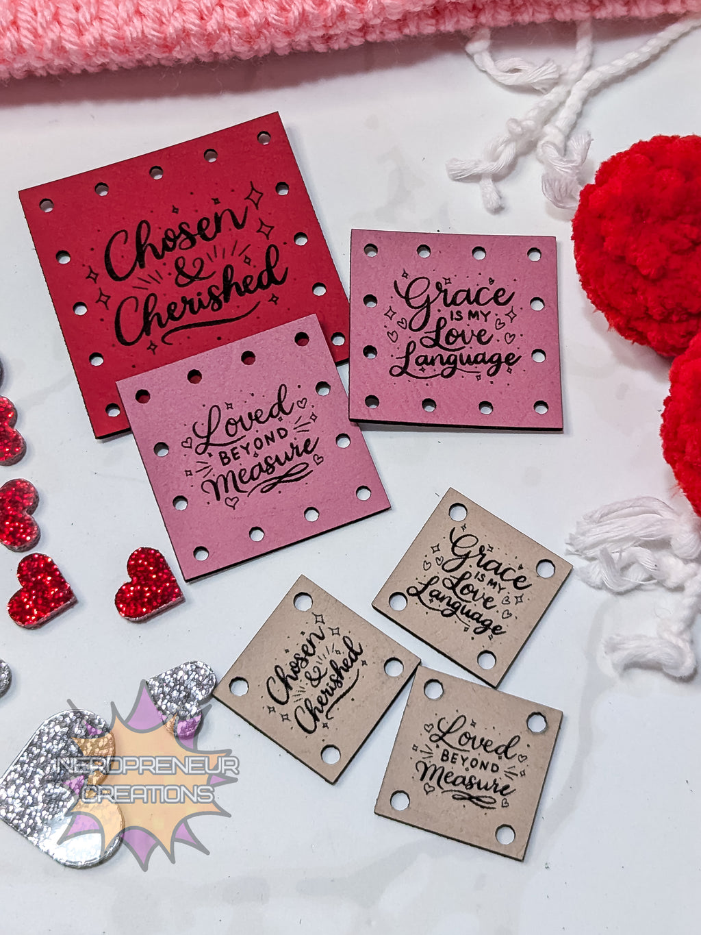 Decorative faux leather patches with motivational phrases on a white surface with red and pink accents.