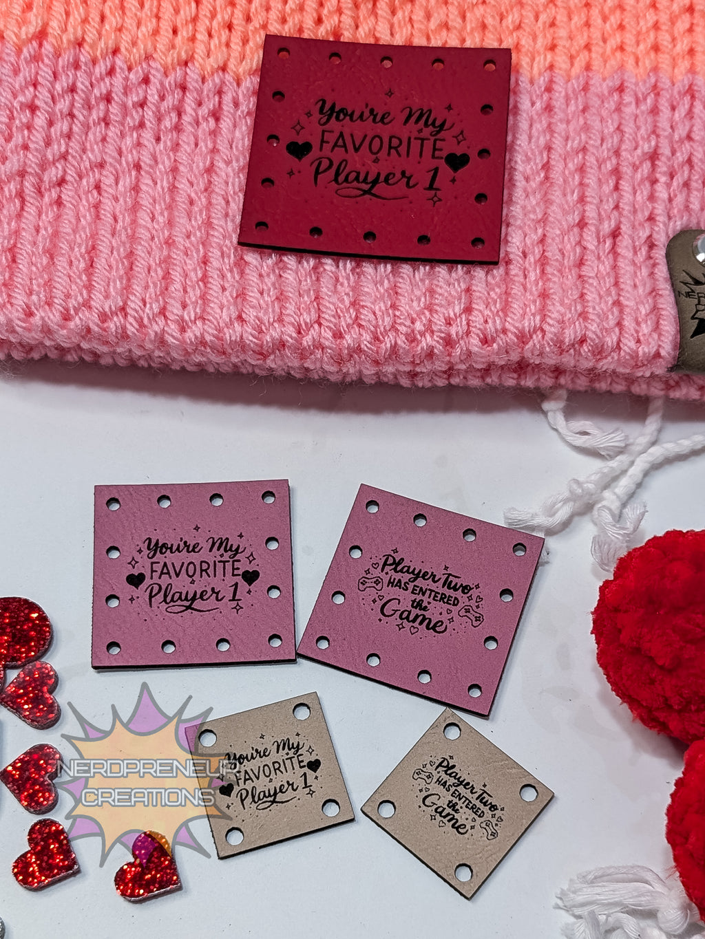 Faux leather patches with engraved text on a pink textured surface with decorative elements.