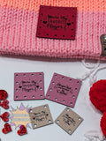Faux leather patches with engraved text on a pink textured surface with decorative elements.