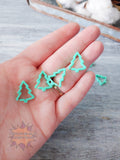 Green Christmas tree 3D printed stitch markers on a hand with a wooden surface in the background