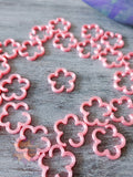 Pink flower 3D printed stitch markers on a wooden surface