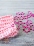 Pink crocheted item and pink star 3D printed stitch markers on a wooden surface